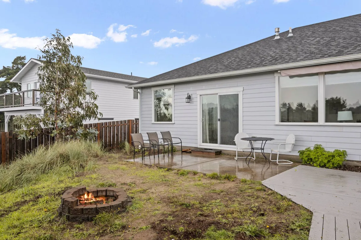 An inviting outdoor patio features a fire pit surrounded by comfortable seating, with glass sliding doors connecting the space to the home. The setting is ideal for family gatherings, outdoor dining, or unwinding while taking in lakeside views, echoing the section's mention of relaxing at the retreat.