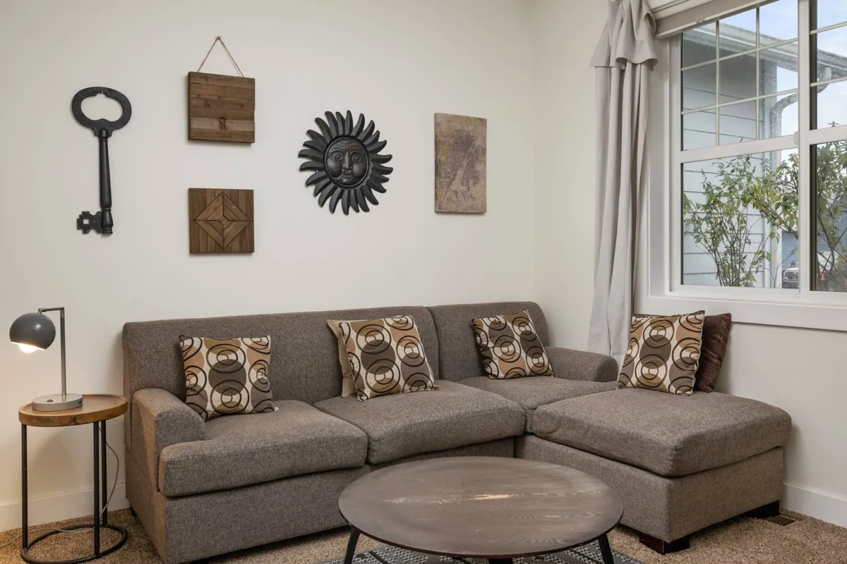 A cozy living room scene featuring a plush sofa, decorative wall art, soft lighting from a table lamp, and a modern coffee table. The arrangement invites relaxation and intimate conversations, creating an inviting atmosphere for couples or friends.